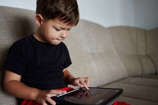istock Toddler draws on a tablet using a finger at home. 1818503582