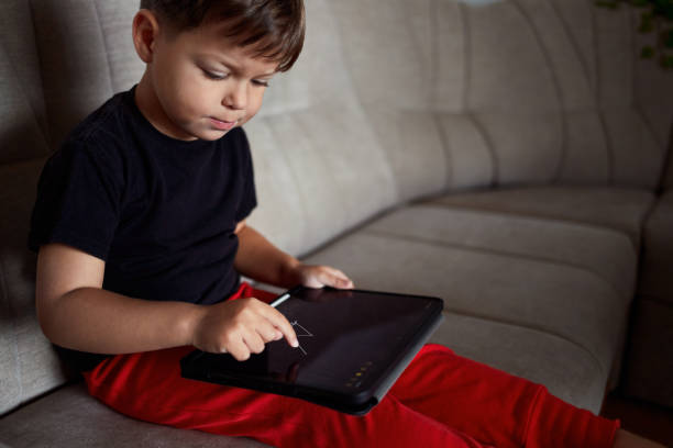 istock Toddler draws on a tablet using a finger at home. 1818503592
