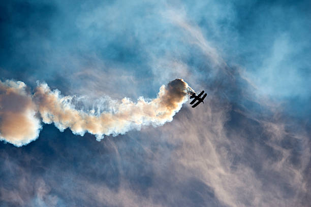 Aerobatic stunt "Aerobatic biplane with smoke against blue sky, low angle view" airplane crash stock pictures, royalty-free photos & images