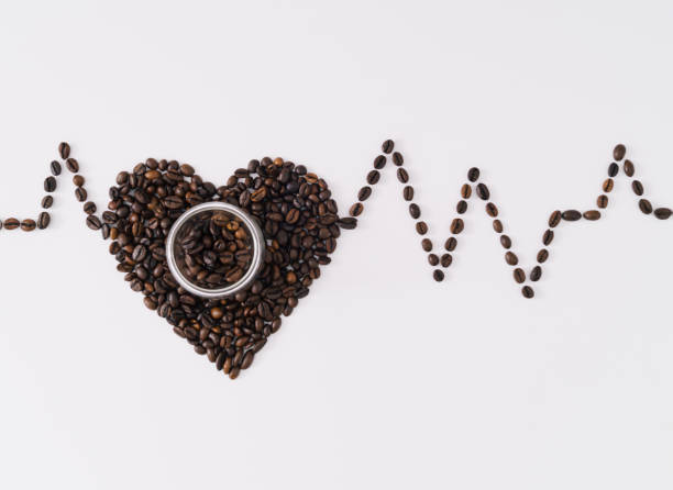 istock Creative layout with heart shape made of roasted coffee beans and coffee cup showing relationship between coffee drinking and cardiovascular disease. Risk or benefit? Unique flat lay. Minimal concept. 1818519585