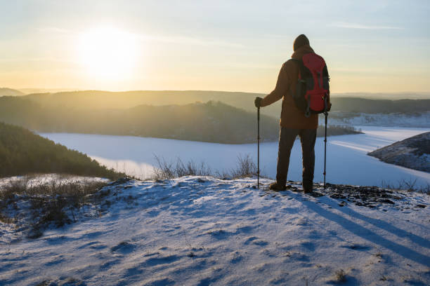 istock Man with backpack, traveller or explorer standing on top of cliff at sunset and looking on valley. 1818527144