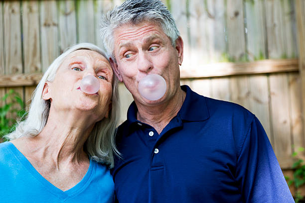 payasear feliz pareja senior - chewing gum women bubble blowing fotografías e imágenes de stock