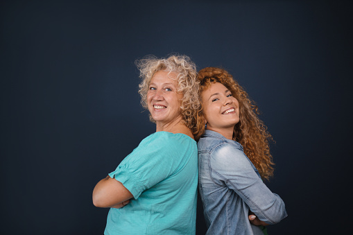 Back to back photo of mother and daughter with curly hair
