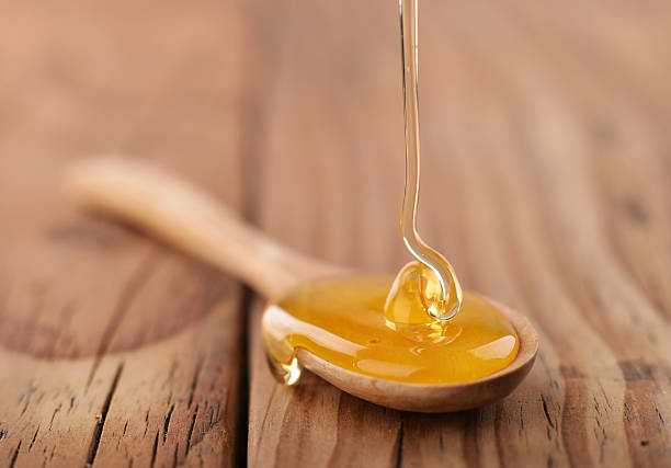 Honey dripping on a wooden spoon stock photo