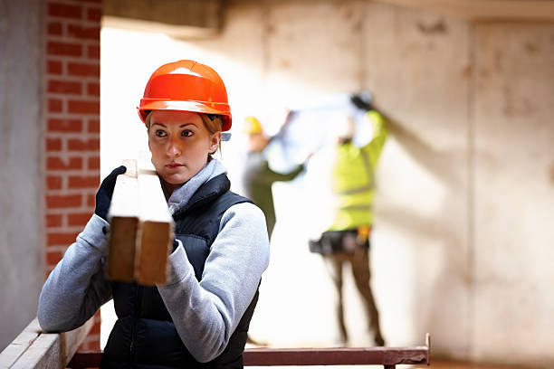 istock Female construction worker carrying wood at work site 181854677