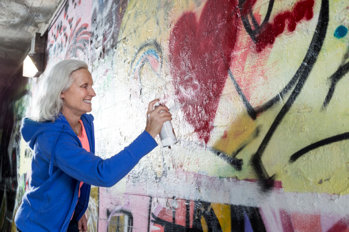 Senior woman spray painting graffiti.