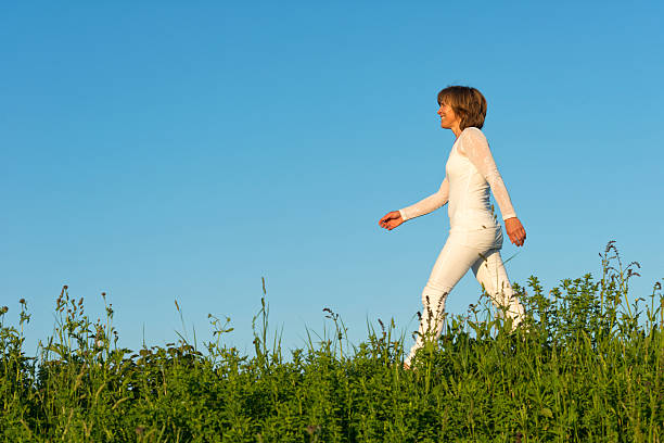 smiling mature woman in white going on meadow