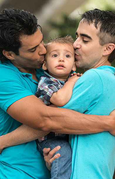 Parents and child Gay men couple posing kissing their child in the city three way kiss stock pictures, royalty-free photos & images