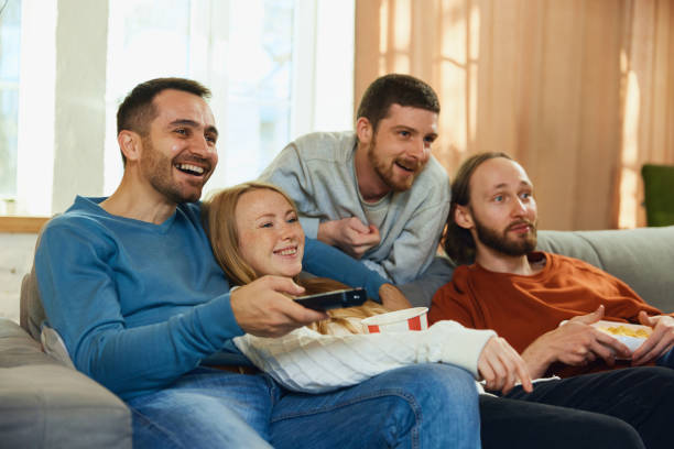 istock Shocked young attractive people with wide smile, laughing watching movie with comedy plot sitting on sofa in living room. 1818550387