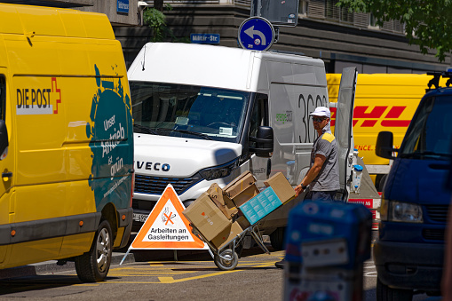 Mailman with cart delivering parcels at Swiss City of Zürich on a hot sunny summer day. Photo taken July 11th, 2023, Zurich, Switzerland.