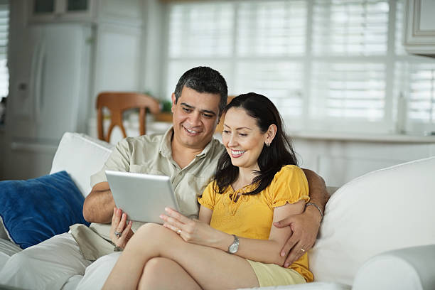 Happy couple looking at smart tablet on a sofa
