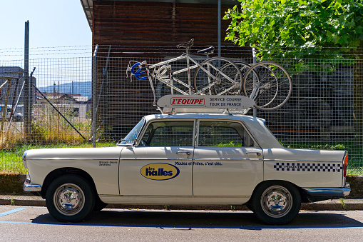 White classic car Peugeot Tour de France service car with racing bicycles on the roof at City of Zürich on a hot and sunny summer day. Photo taken July 11th, 2023, Zurich, Switzerland.