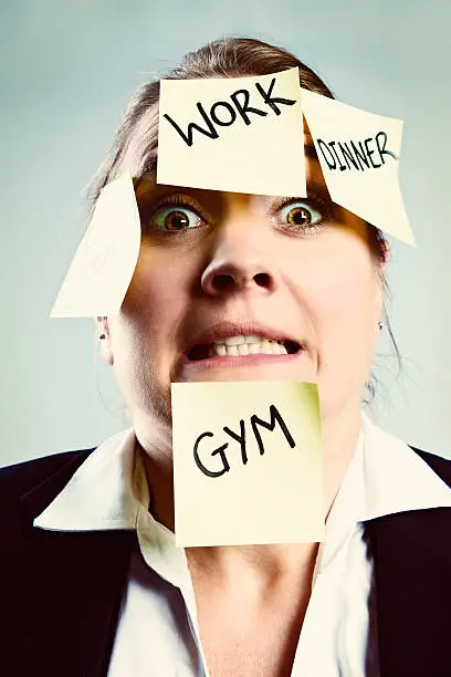 Photo of Overworked and overwrought woman covered in sticky task reminders