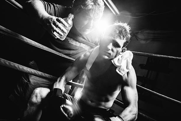 Boxer Coach encourages Boxer sitting in the boxing ring corner. lightweight weight class stock pictures, royalty-free photos & images
