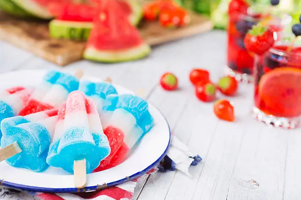 Homemade red-white-and-blue popsicles on an outdoor table.