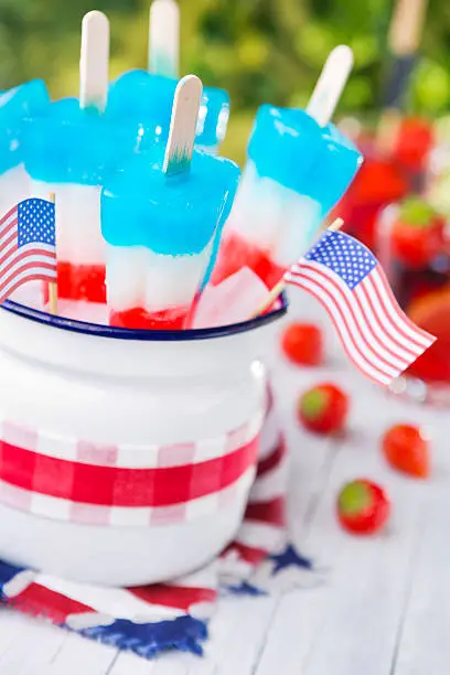 Homemade red-white-and-blue popsicles on an outdoor table.