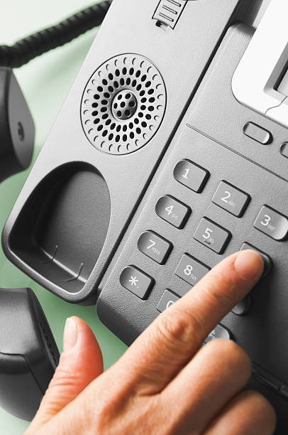 Business telephone with hand dialling number Operators hand operating a traditional Office telephone dialling phone stock pictures, royalty-free photos & images