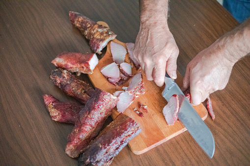 The chef cuts raw veal on a cutting board with a knife before cooking. Asian food. Hotel Recipe Idea.