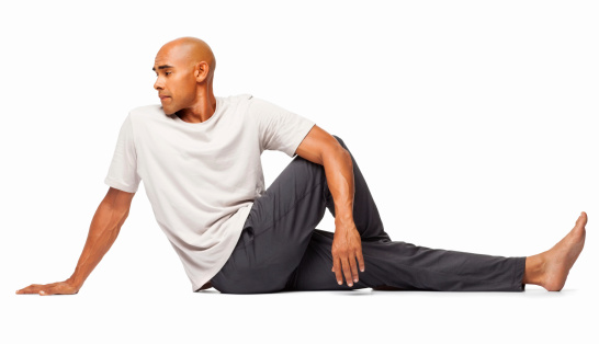 Fitness African American man sitting in a spinal twist posture on floor. Horizontal shot. Isolated on white.