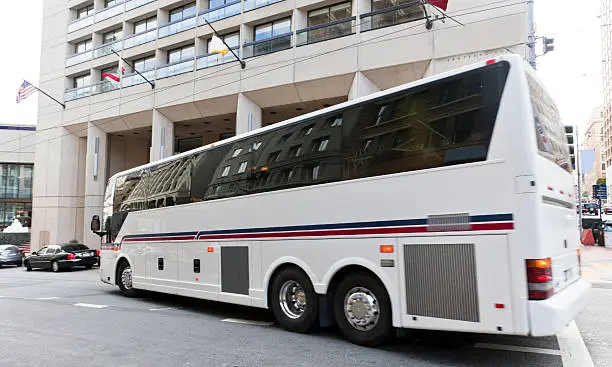 Tour bus making left-hand turn in front of hotel. Focus on front of bus. Horizontal.