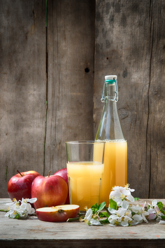 Bottles with different kinds of homemade apple juice on a rustic background. Softly toned with some grain added. 