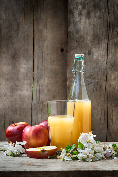 Fresh homemade apple juice in a glass & bottle with apples Bottles with different kinds of homemade apple juice on a rustic background. Softly toned with some grain added.  apple juice photos stock pictures, royalty-free photos & images