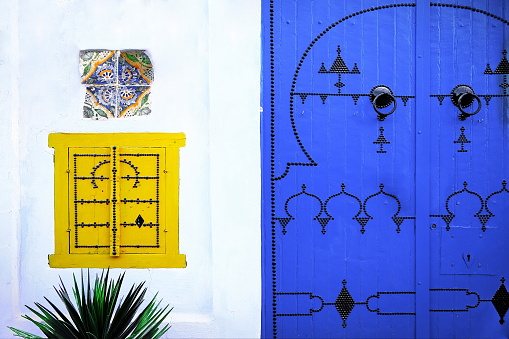 Detail of traditional colorful door, window and weathered ceramic tiles in Medina of Kairouan. It has been on the UNESCO World Heritage List since 1988, Tunisia