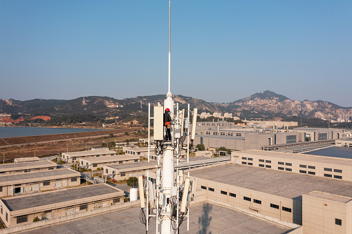 Engineer working on telecommunications tower under the sky