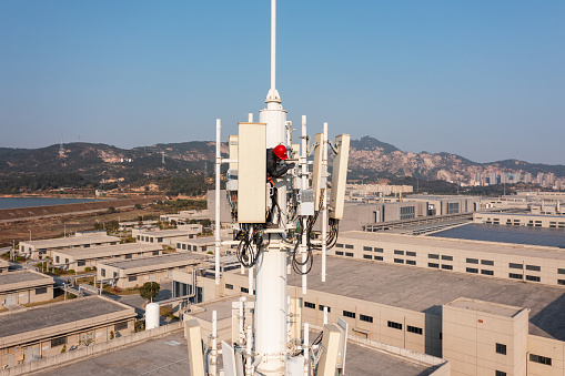 Engineer working on telecommunications tower under the sky