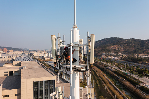 Engineer working on telecommunications tower under the sky