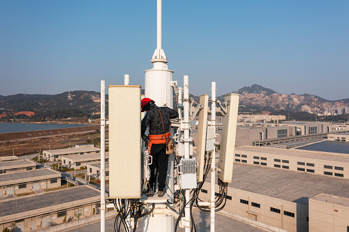 Engineer working on telecommunications tower under the sky