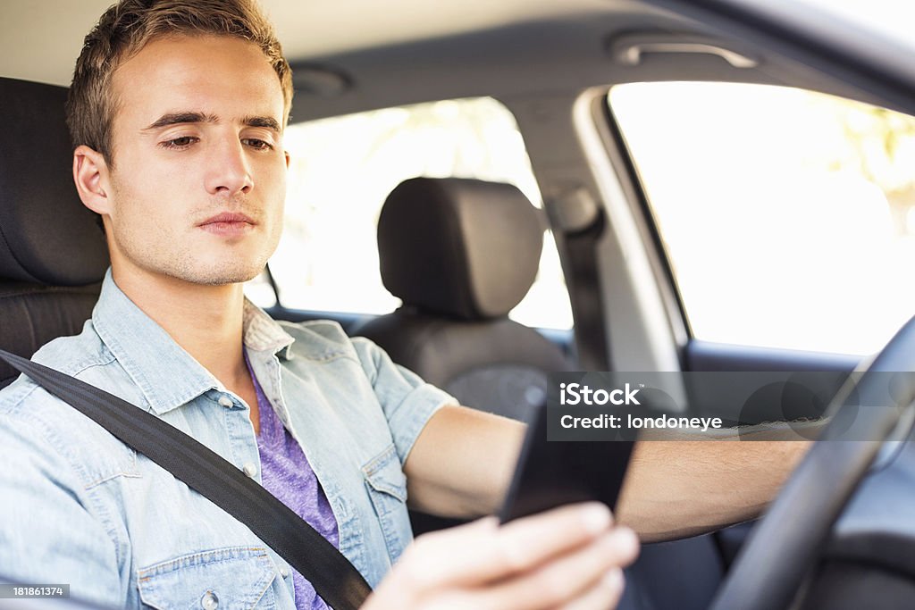 Jovem homem mensagens de texto enquanto dirige Car - Foto de stock de 16-17 Anos royalty-free