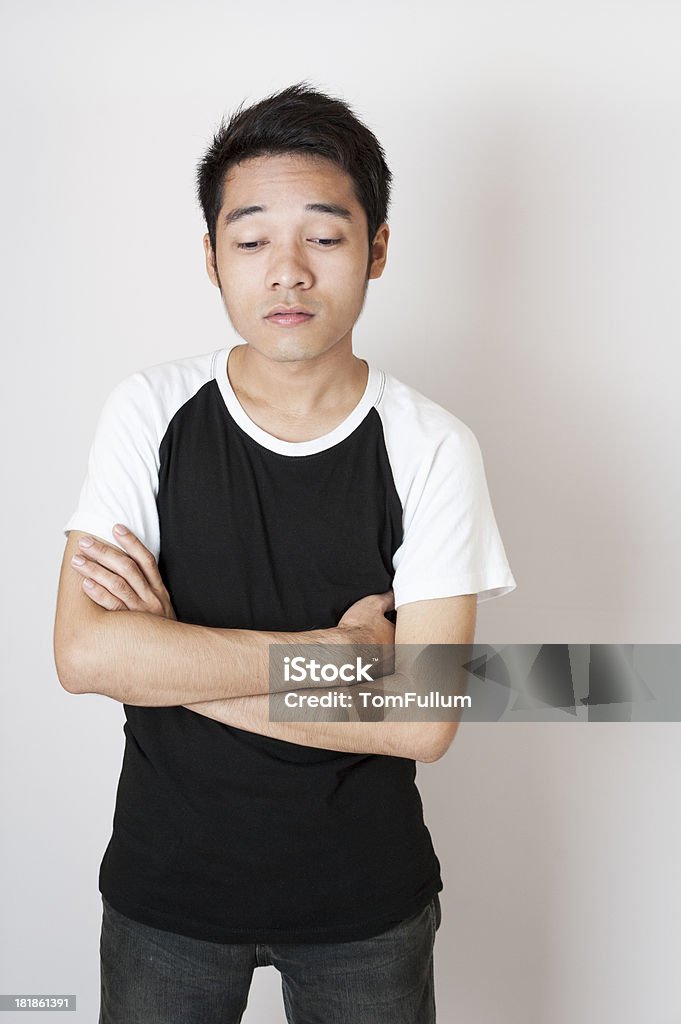 Filipino Man Young asian man looking down in contemplation against white wall Adult Stock Photo