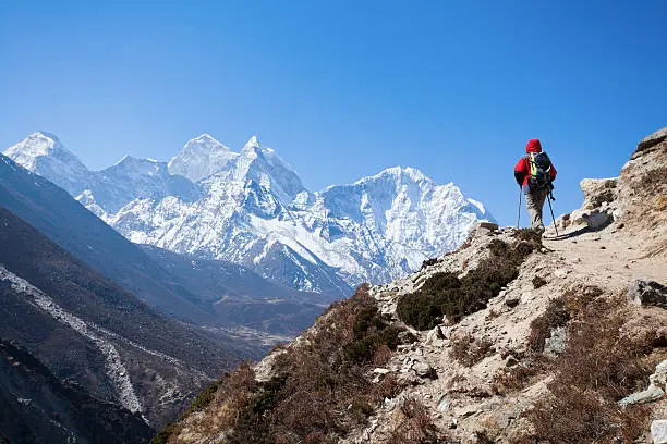 Hiker walking on the treek towards the majestic mountain peaks of the Himalayas.