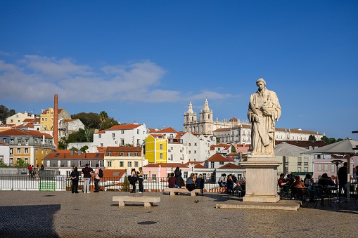 Lisbon, Portugal - Nov 14, 2023: The Statue of Saint Vincent, located in Alfama district, overlooks the harbour on Douro River. Igreja de São Vicente de Fora church in the background.