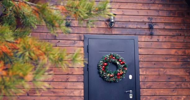 Country house awaits family for Christmas celebration. Door with Christmas wreath sets tone for family festivity. Cozy, welcoming ambiance for family holiday, wreath symbolizing festive spirit. la casa de campo espera a la familia para la celebración de navidad. la puerta con corona de navidad marca el tono de la festividad familiar. ambiente acogedor y acogedor para las vacaciones familiares, corona que simboliza el espíritu festivo.