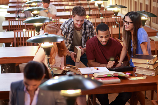 A young adult female student is sitting at the table in the library, studying for her upcoming exams.