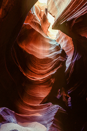 Antelope Canyon, slot canyon in the American Southwest in Arizona with deep shades of purple, orange and beams of light from above to the canyon floor.