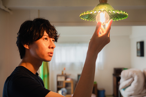 Young man changing an incandescent light bulb