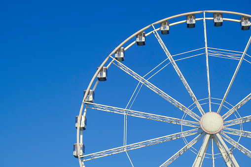 Ferris wheel across blue sky in the promenade of Rimini from beneath