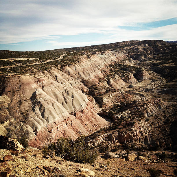 desert badlands against a cloud filled sky stretch to the horizon beyond. the wilderness surrounding grand junction colorado offers such natural wonder and sprawling landscapes. square mobilestock composition with retro color treatment.