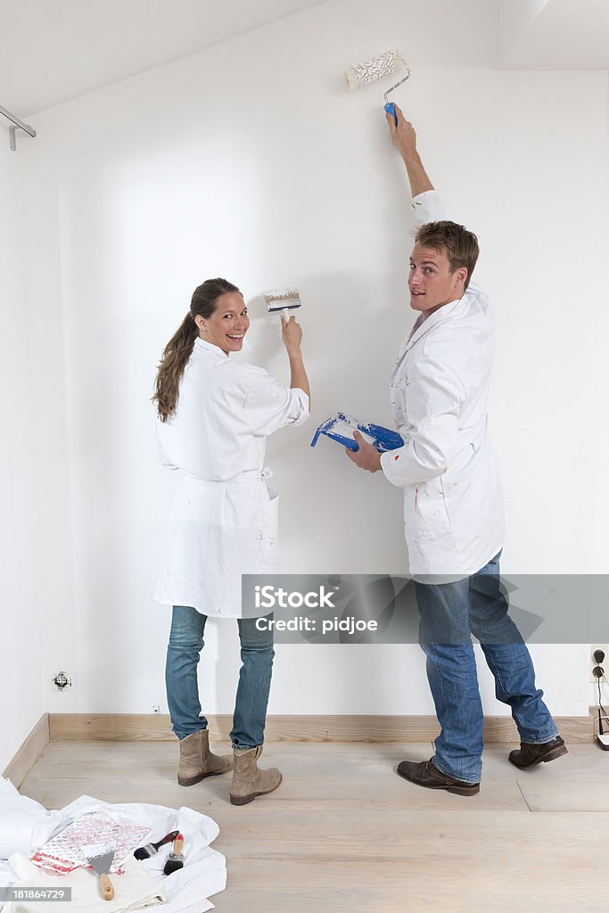 Pareja feliz pintura de pared en la sala de estar - Foto de stock de Pintar libre de derechos