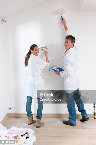 Pareja Feliz Pintura De Pared En La Sala De Estar Foto de stock y más banco de imágenes de Pintar - Pintar, Adulto, Adulto joven