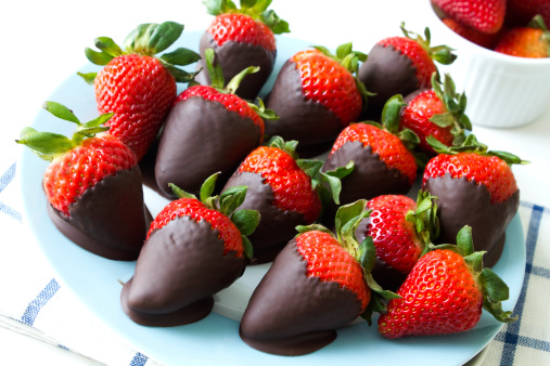A close up shot of fresh strawberries dipped in dark chocolate.