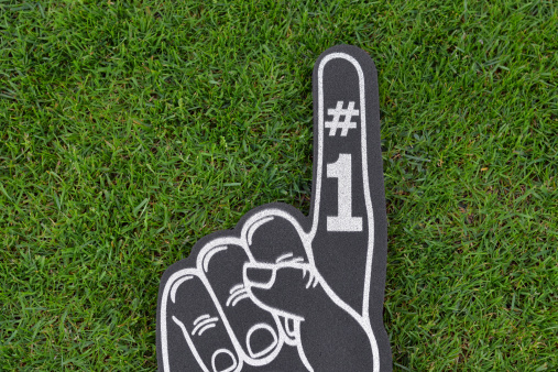 Close up of a sports foam finger on grass symbolizing a Number One team in field sports.  See also
