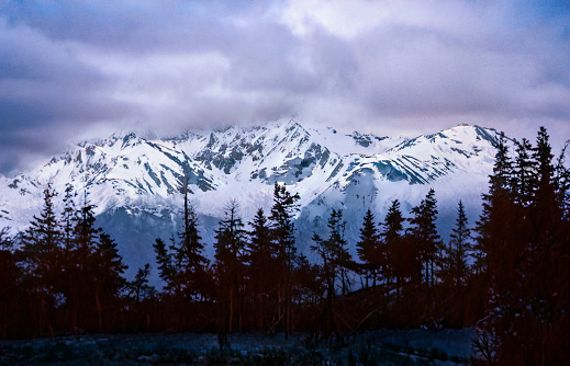 Dusk colored sky accents the early snow fall that has covered the mountain range in Alaska.
