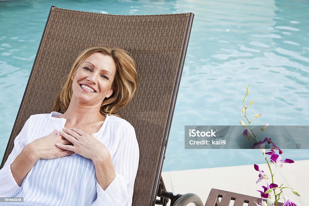 Mulher Madura relaxante à beira da piscina - Foto de stock de Mão no Peito royalty-free