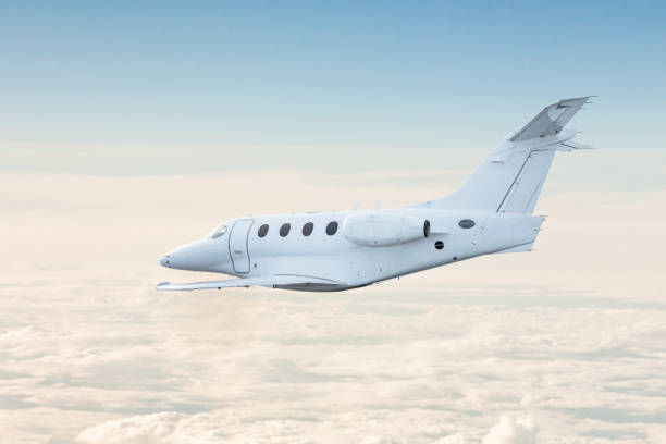 istock White private jet fly in the air above the clouds 1818658382