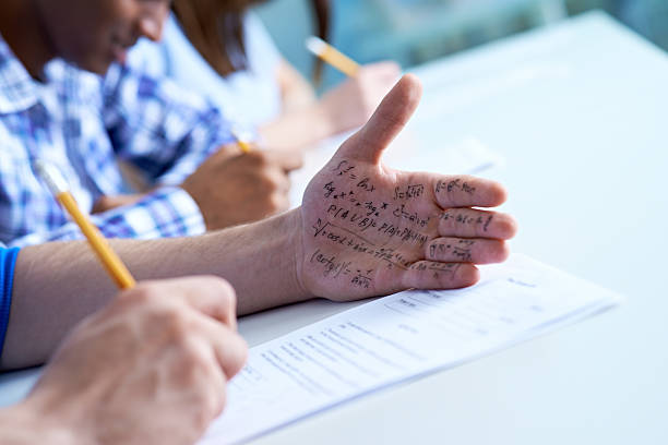 Cheating on a test Student using a cheat sheet for his test two faced stock pictures, royalty-free photos & images