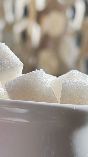 The sugar cubes are neatly arranged in a transparent glass sugar bowl.